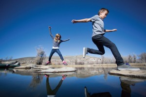 Children jumping rocks in pond